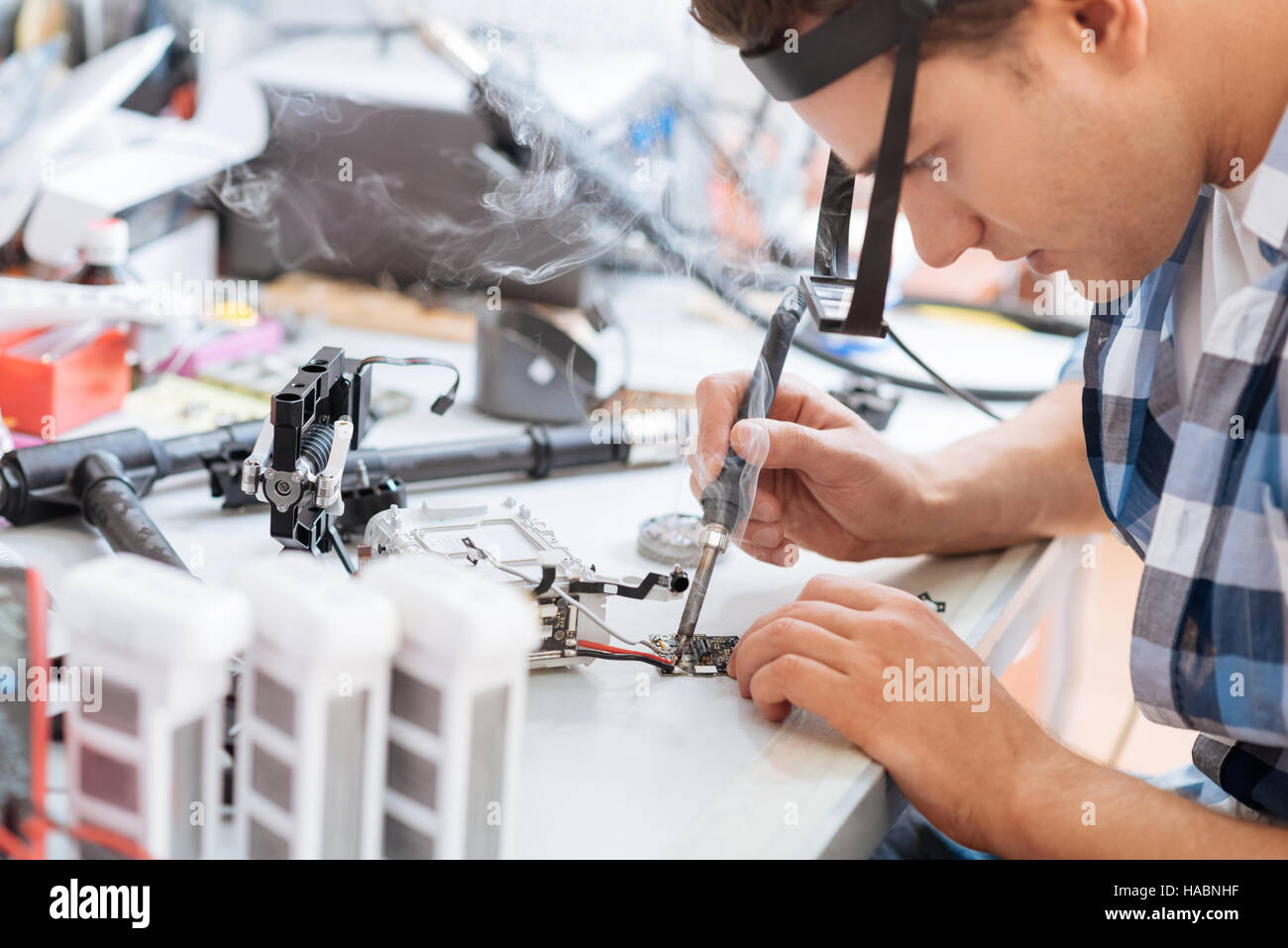 Delighted man soldering drone details attentively Stock Photo Alamy