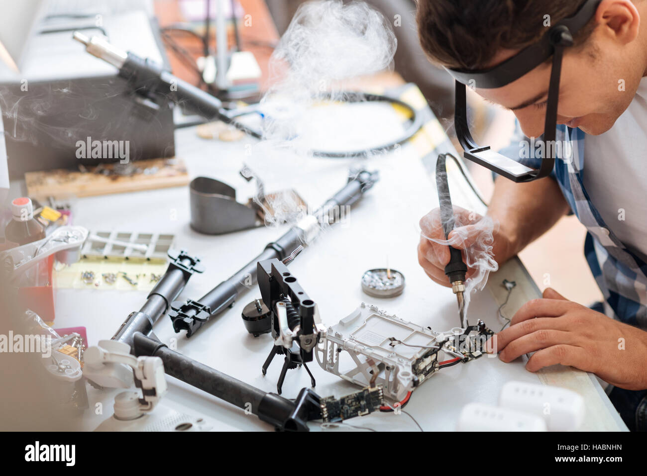 Hardworking man soldering drone details attentively Stock Photo