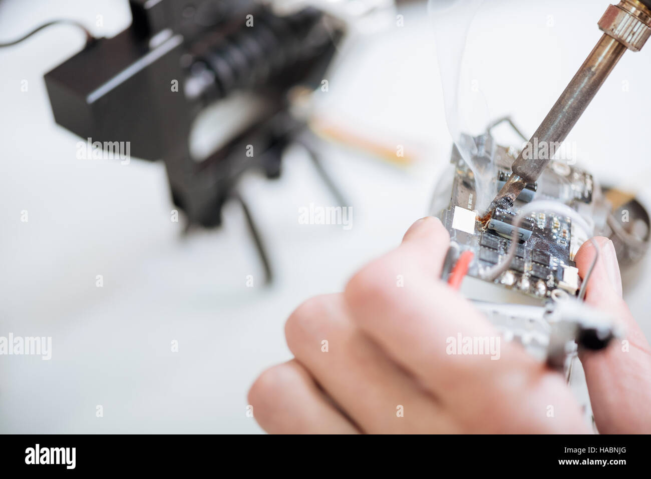 Close up of mans hands holding chip and soldering iron Stock Photo