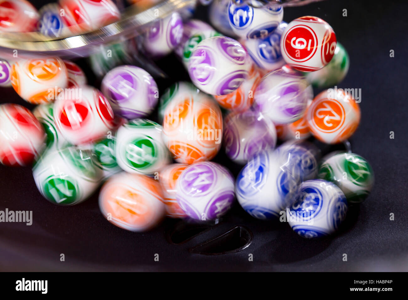 Colourful lottery balls in a sphere in motion. Gambling machine and euqipment. Blurred lottery balls in a lotto machine. Stock Photo