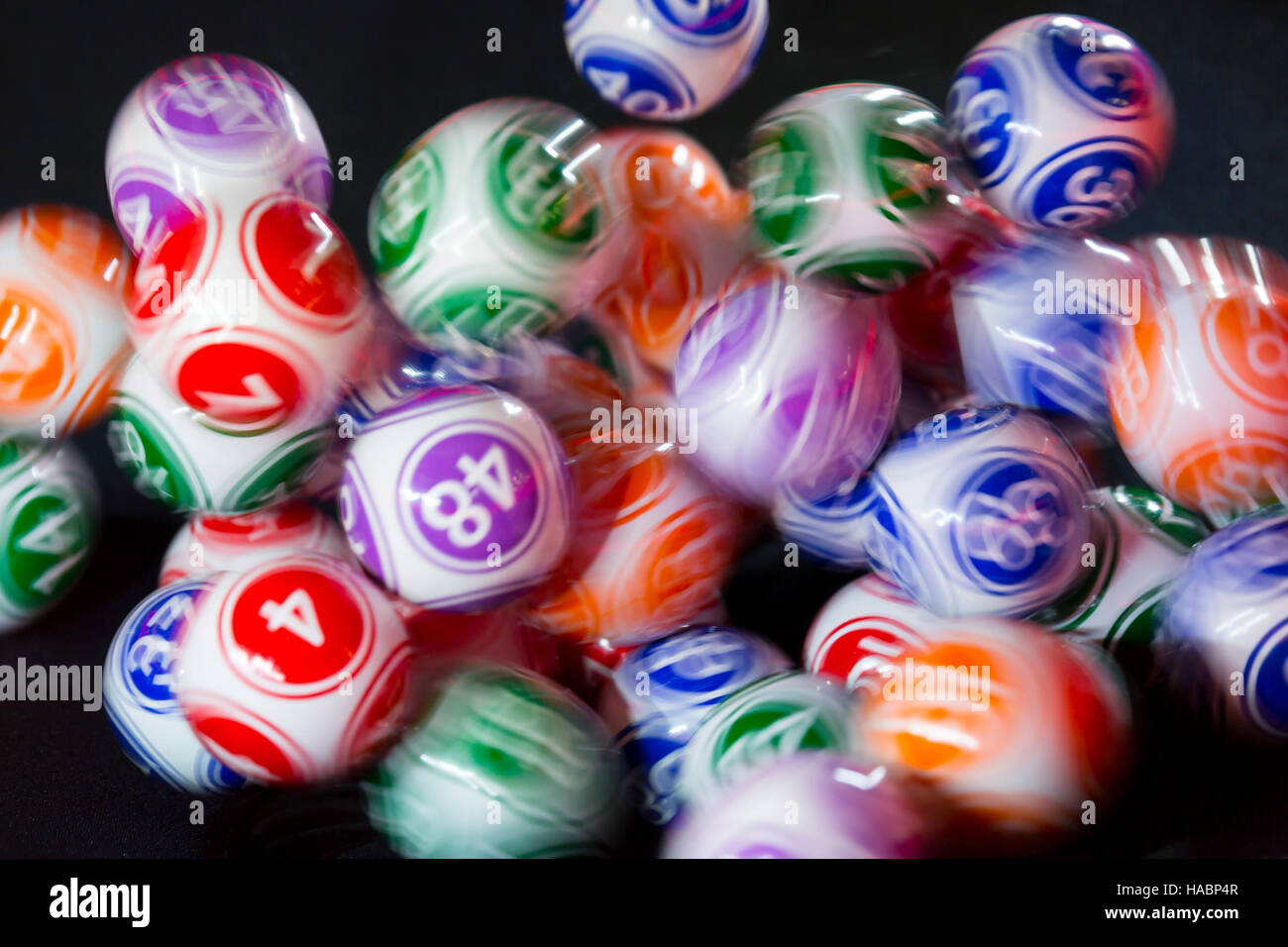 Colourful lottery balls in a sphere in motion. Gambling machine and euqipment. Blurred lottery balls in a lotto machine. Stock Photo