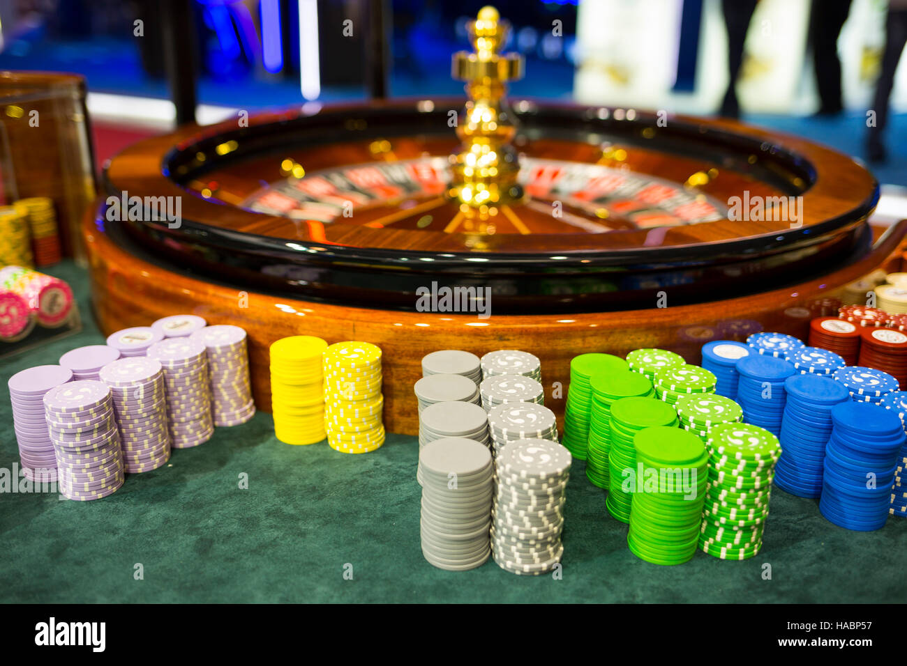 Wooden colourful casino roulette. Casino machine and gambling equipment. Roulette table with chips next to the roulette. Spinning roulette in motion. Stock Photo