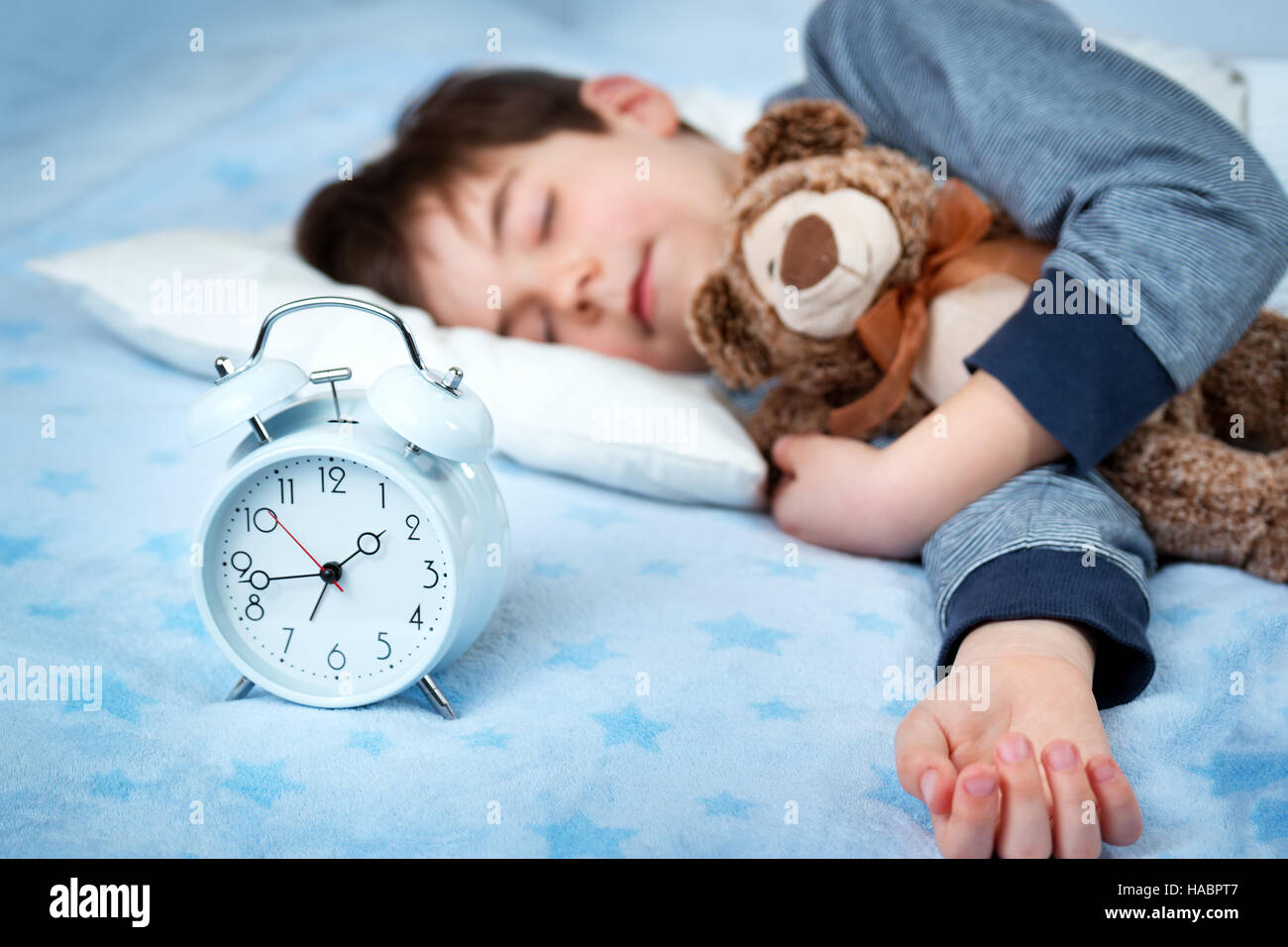 six years old child sleeping in bed with alarm clock Stock Photo Alamy