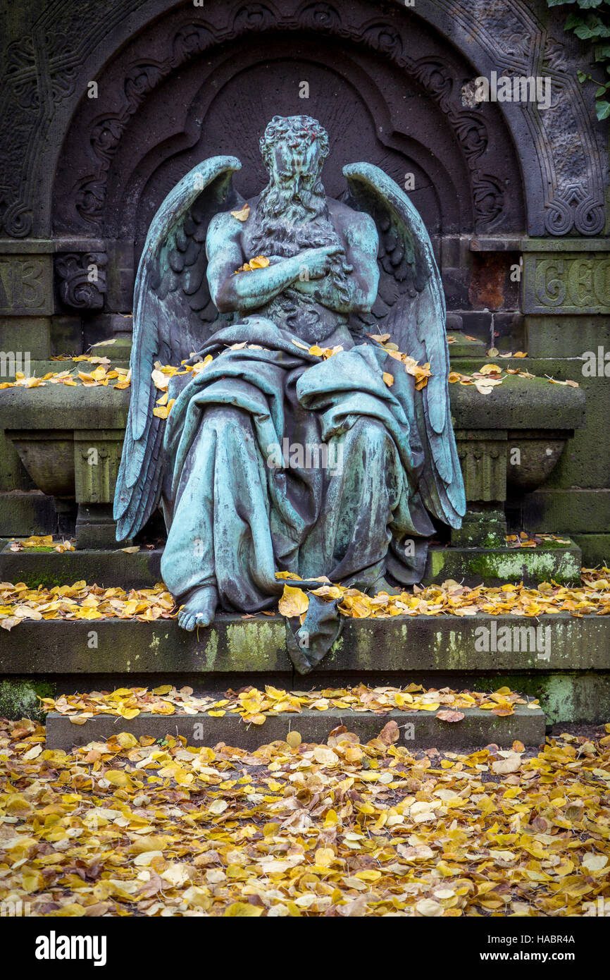 Sculpture of an old weathered arch angel with autumn leaves. Unknown ...