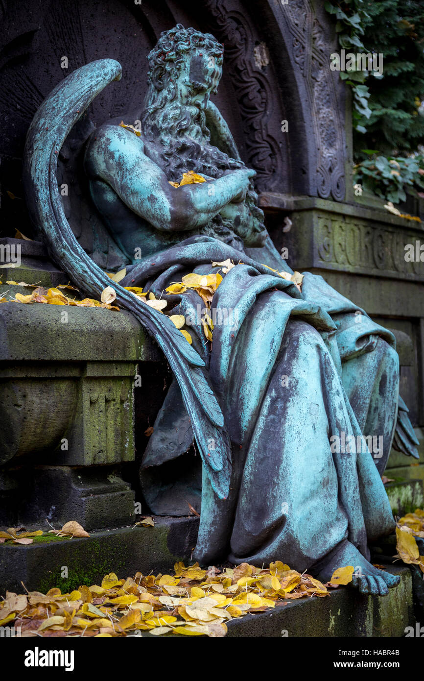 Sculpture of an old weathered arch angel with autumn leaves. Unknown ...