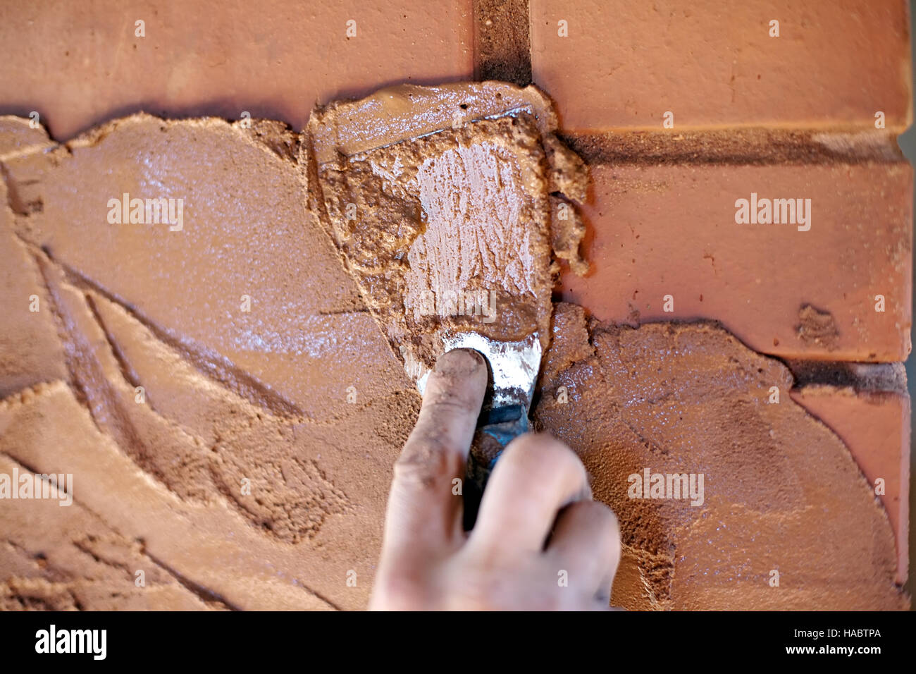trowel in worker hand closeup on red brick wall background Stock Photo