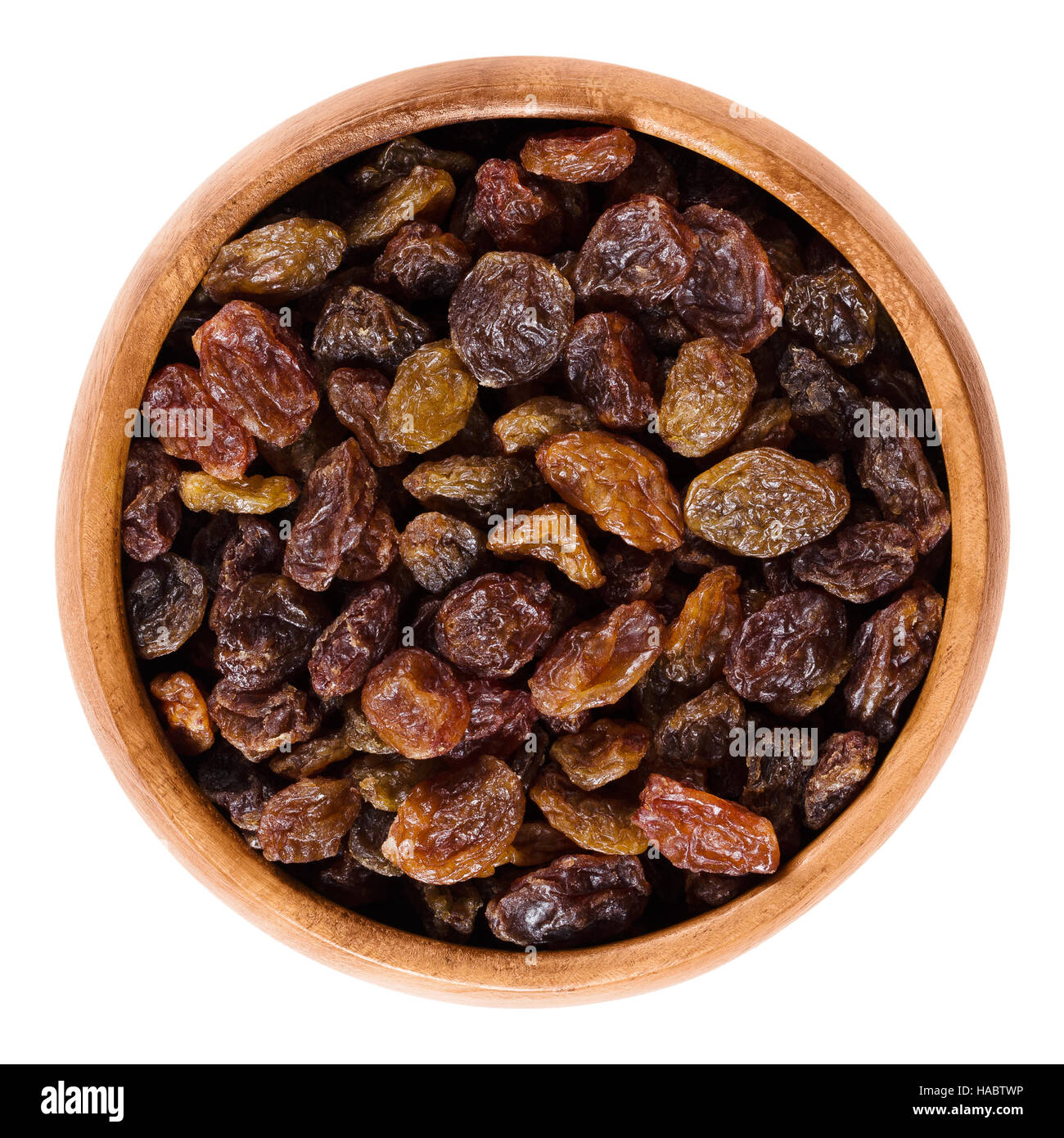 Raisins in wooden bowl made of dark brown colored large grapes. Edible dried seedless fruits, organic and raw. Stock Photo