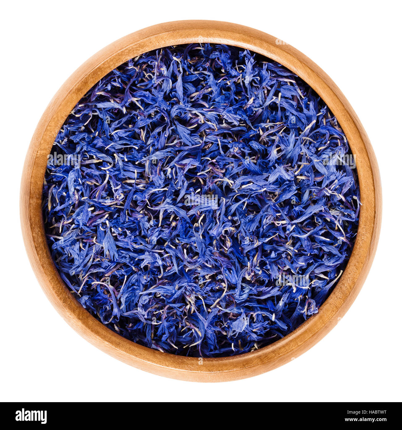 Dried cornflowers in wooden bowl. Edible flowers of Centaurea cyanus with intense blue pigment, used for tea and salads. Stock Photo