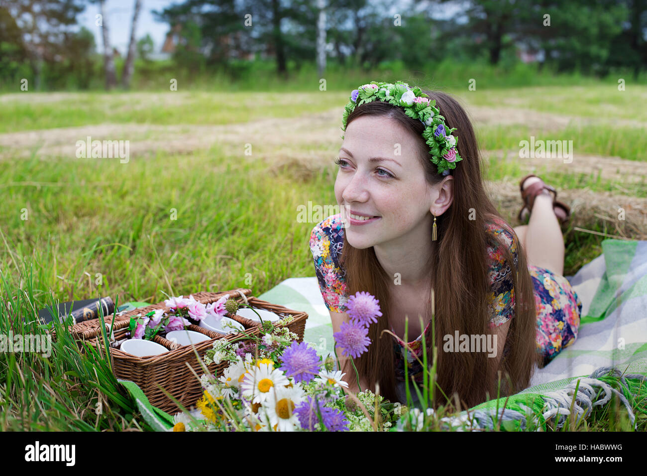 Freckled girl lying on plaid in meadow and looking away Stock Photo