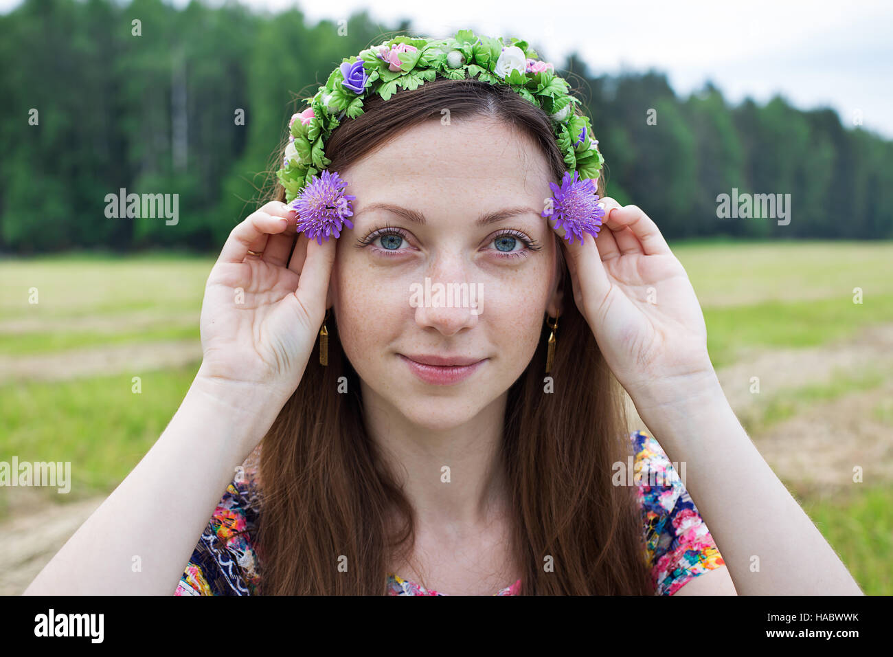 Freckled girl holding two field flowers at eye level Stock Photo