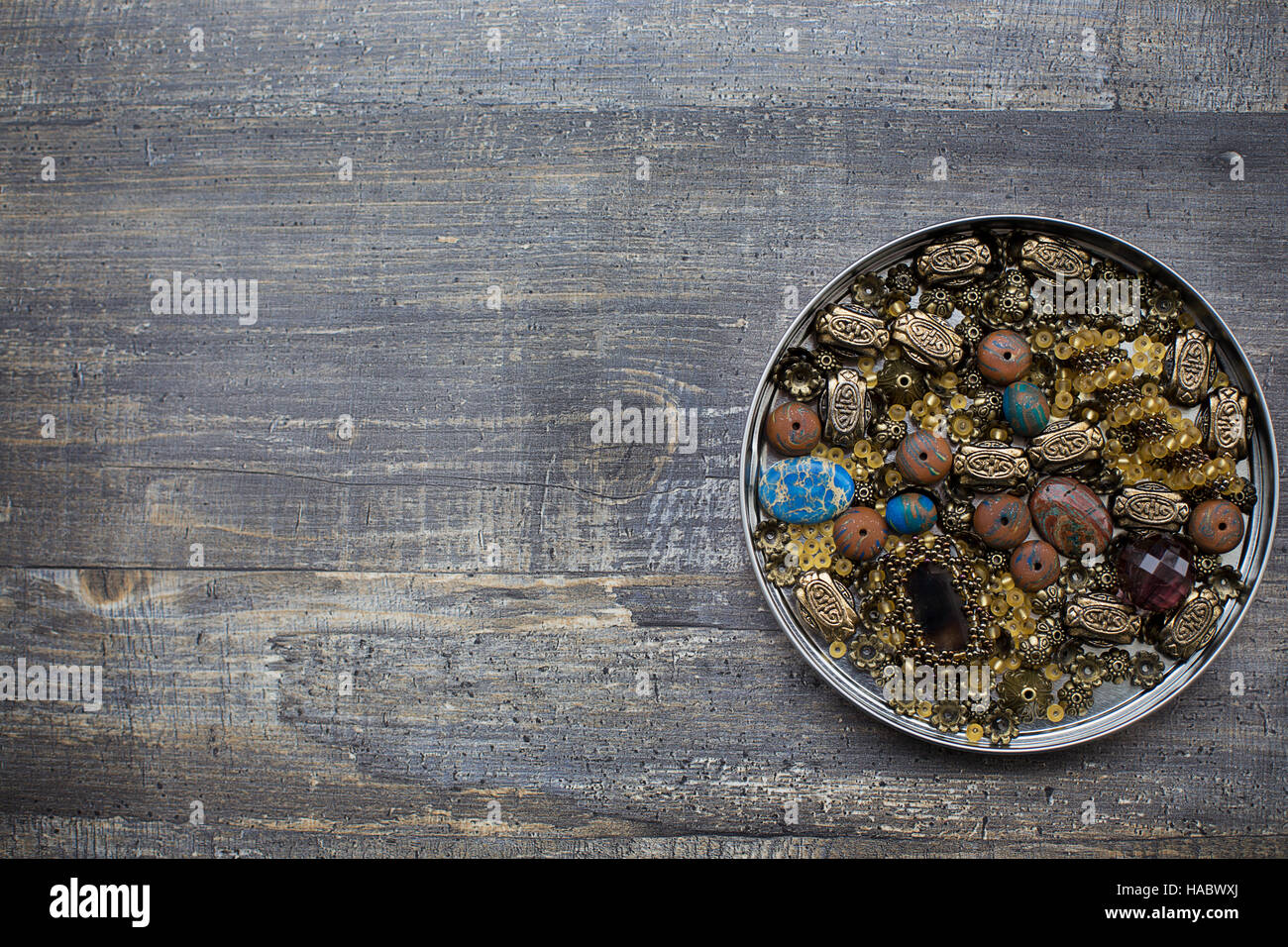Bunch of small beads into tin lid on wooden background Stock Photo