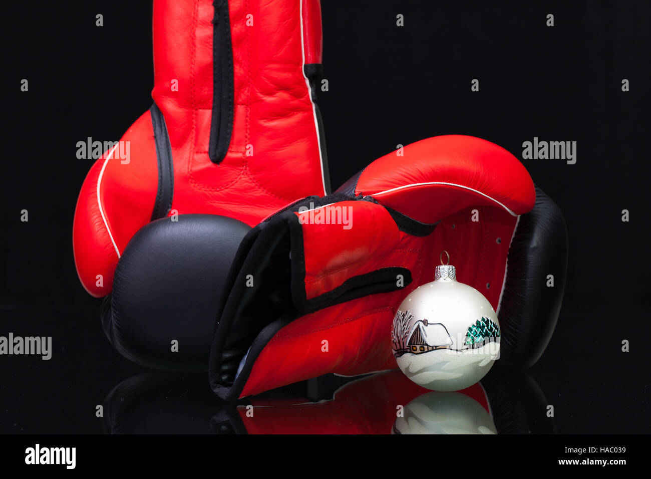 Red and black boxing gloves and Christmas decoration on black glass