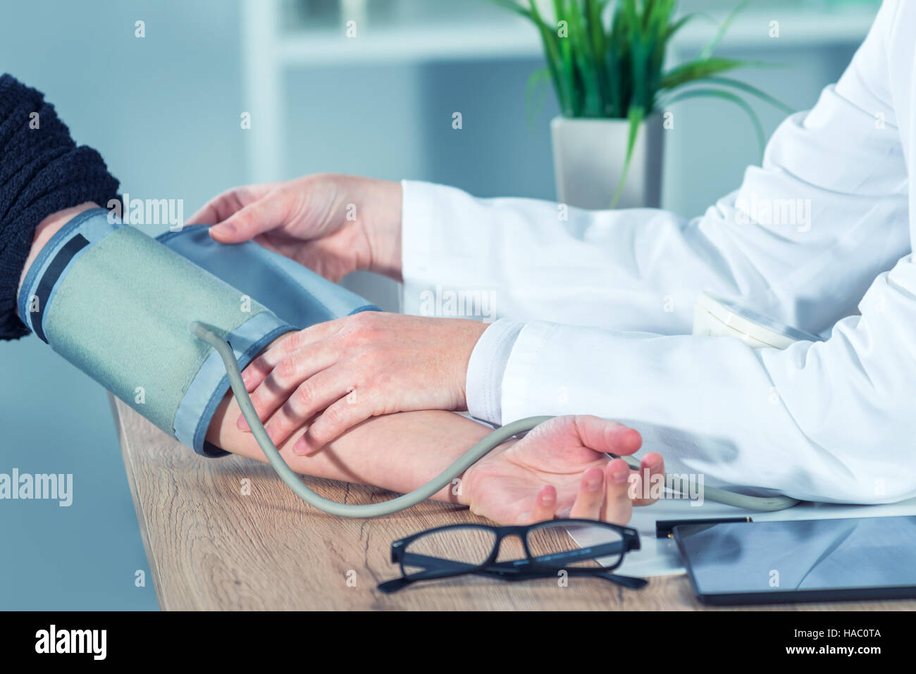 Doctor cardiologist measuring blood pressure of female patient in hospital office, health care control and monitoring Stock Photo