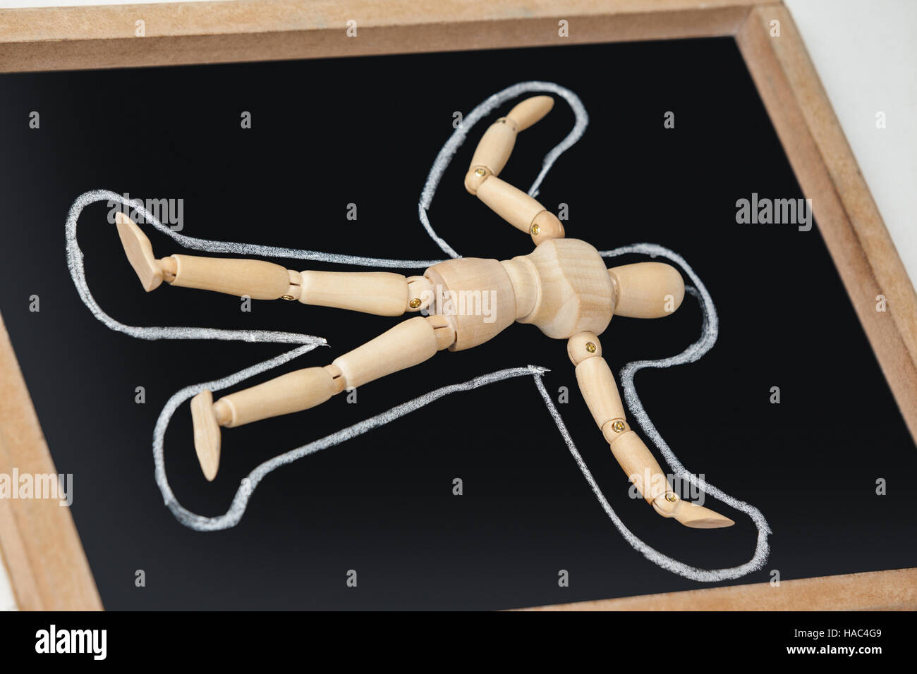 Wooden figurine lying on a slate board with border around his body Stock Photo