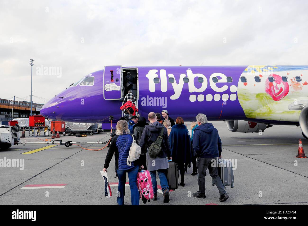 Passengers people carrying luggage getting on plane boarding a Flybe airplane on the tarmac at Cardiff airport in Wales UK Europe 2016    KATHY DEWITT Stock Photo