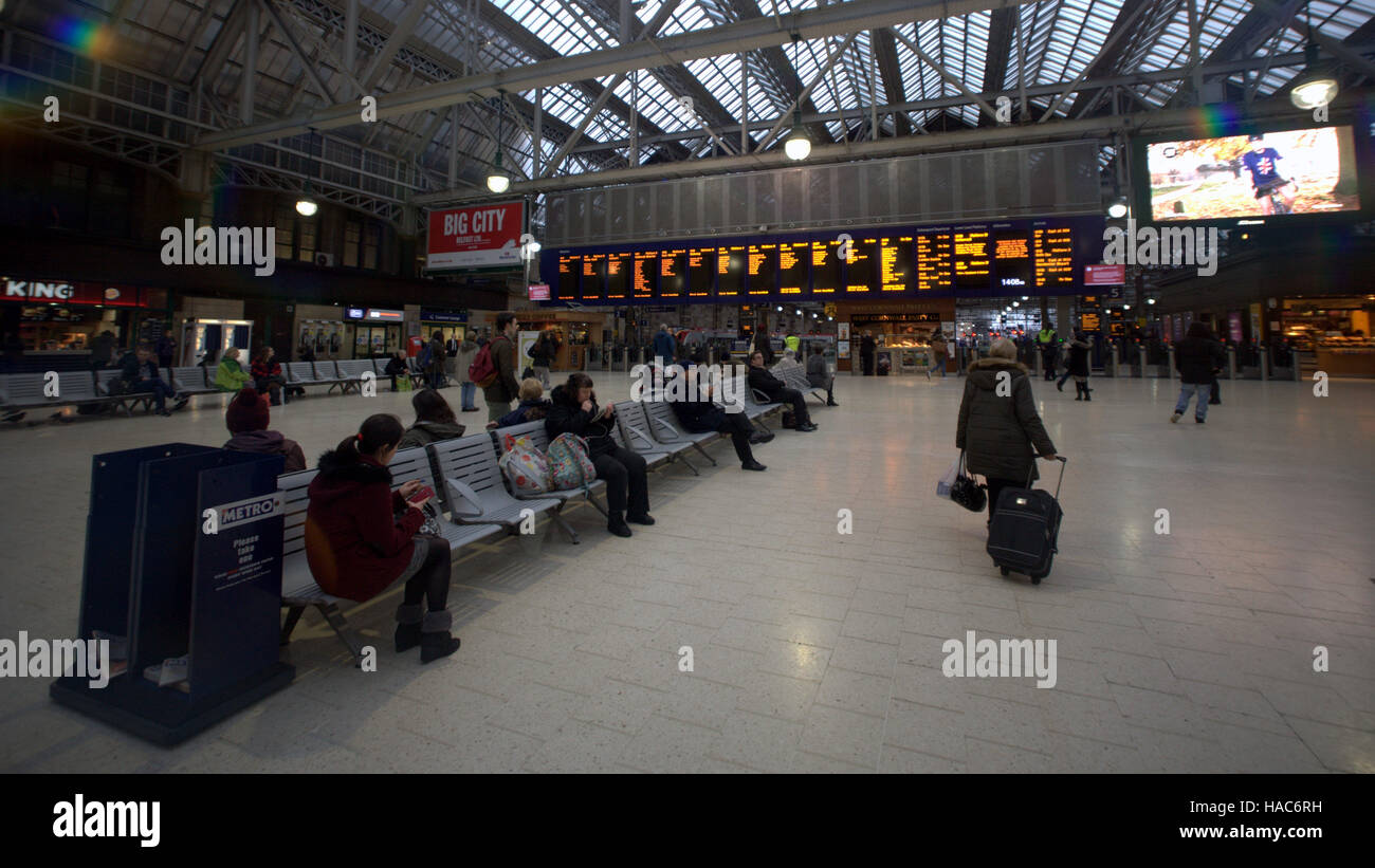 Family in Glasgow central train station phoning looking arrivals board Stock Photo