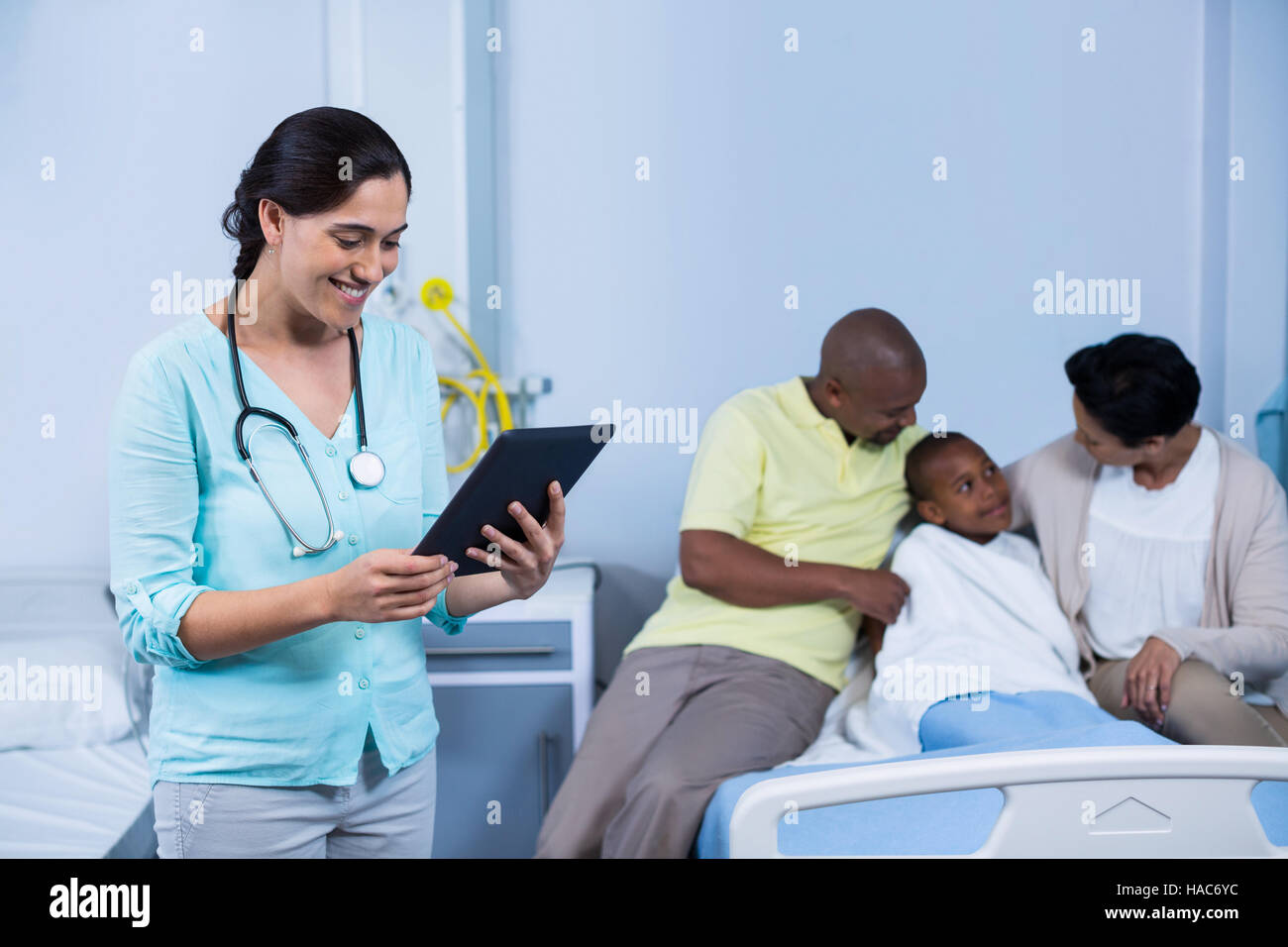 Doctor using digital tablet while parents interacting with patient ...