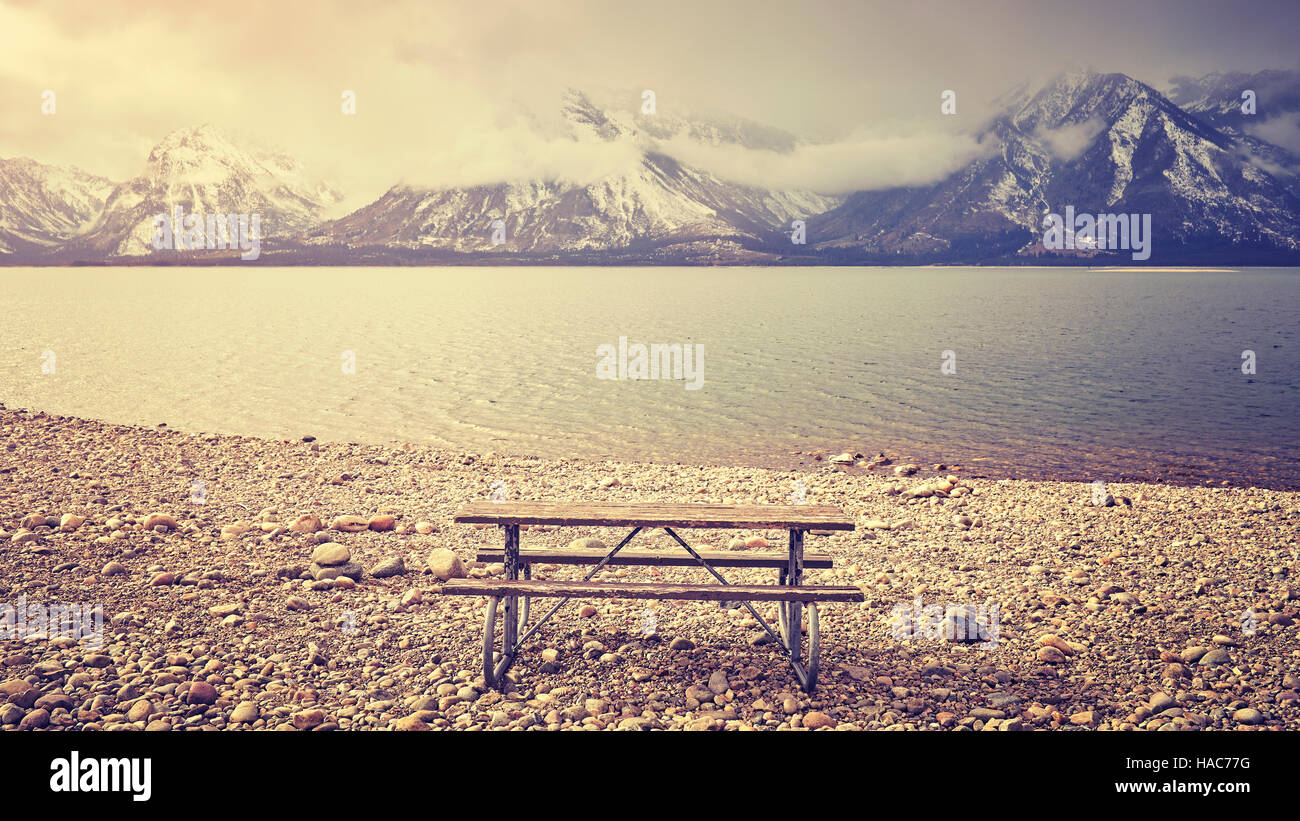 Retro stylized an empty bench with beautiful view over lake, Grand Teton National Park, Wyoming, USA. Stock Photo