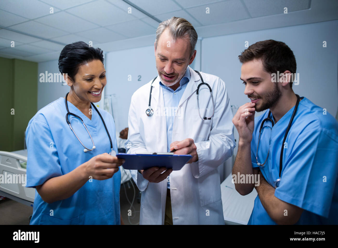 Doctor and nurse discussing over clipboard in ward Stock Photo - Alamy