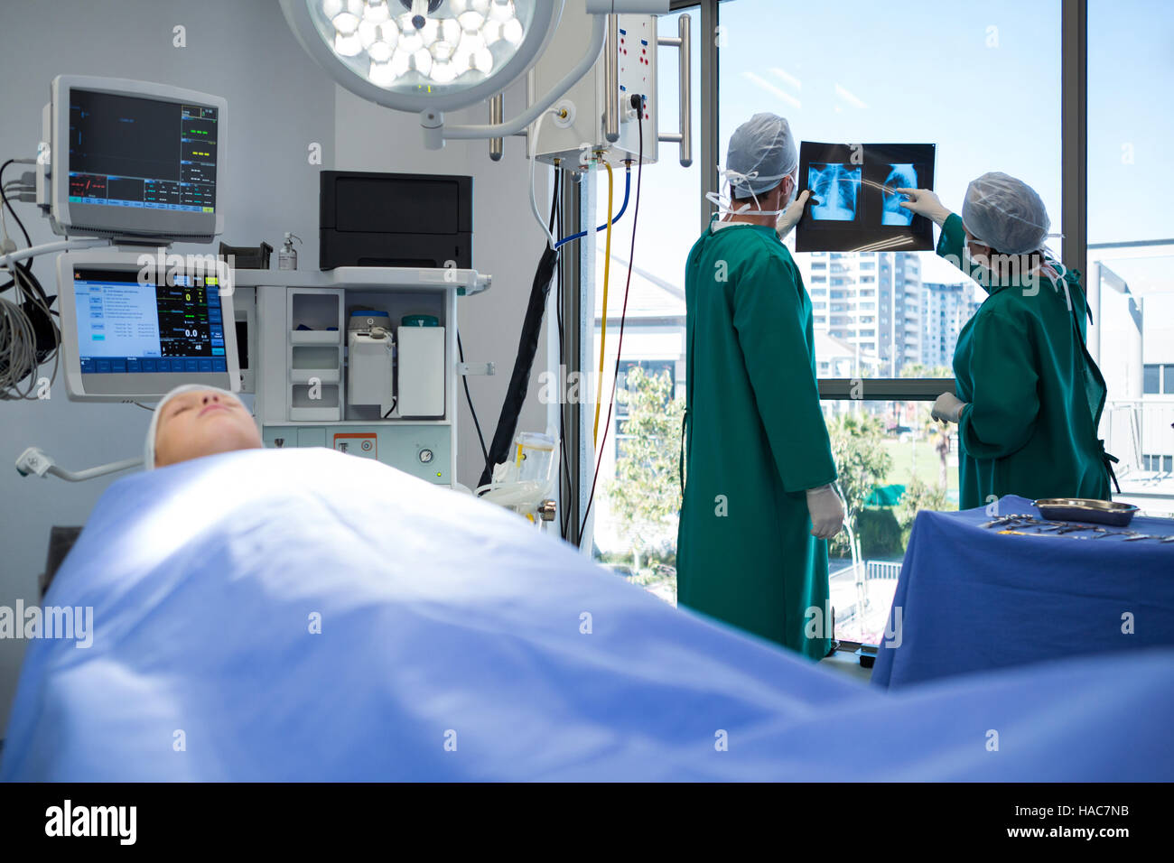 Surgeons discussing x-ray while operating patient Stock Photo - Alamy