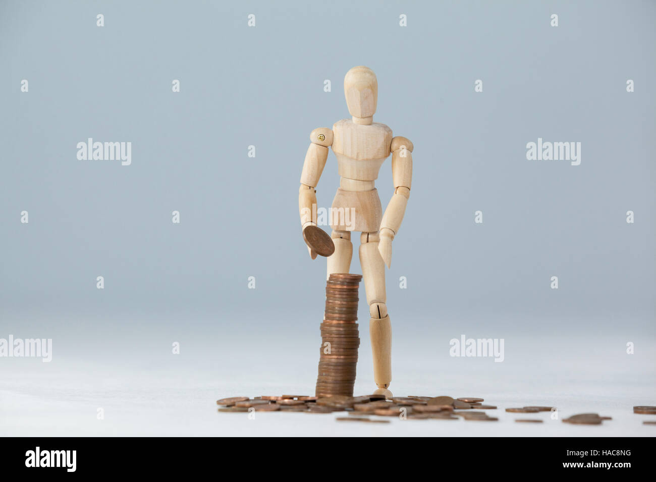Wooden figurine standing and making stack of coins Stock Photo - Alamy