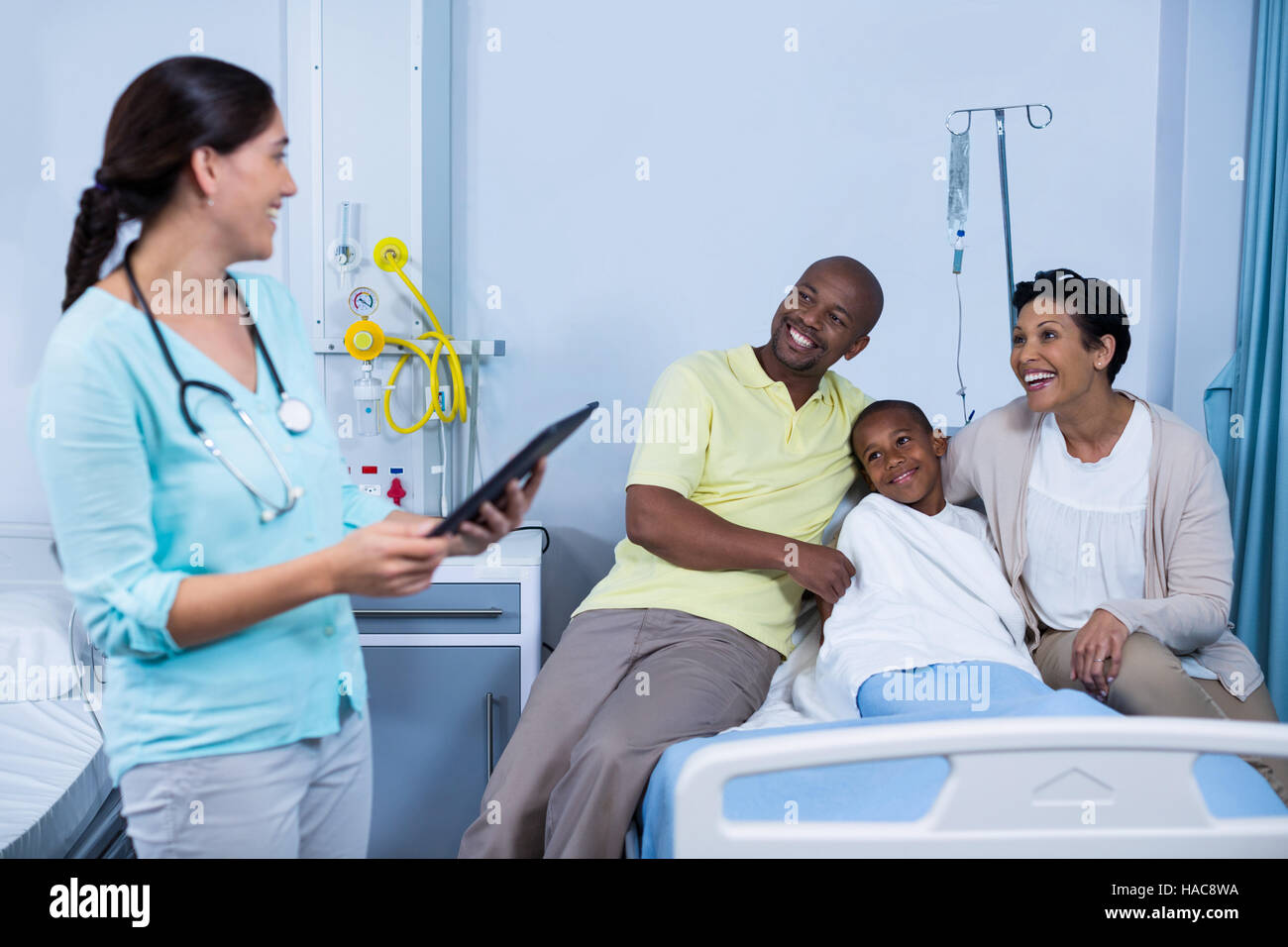 Doctor using digital tablet while parents interacting with patient ...