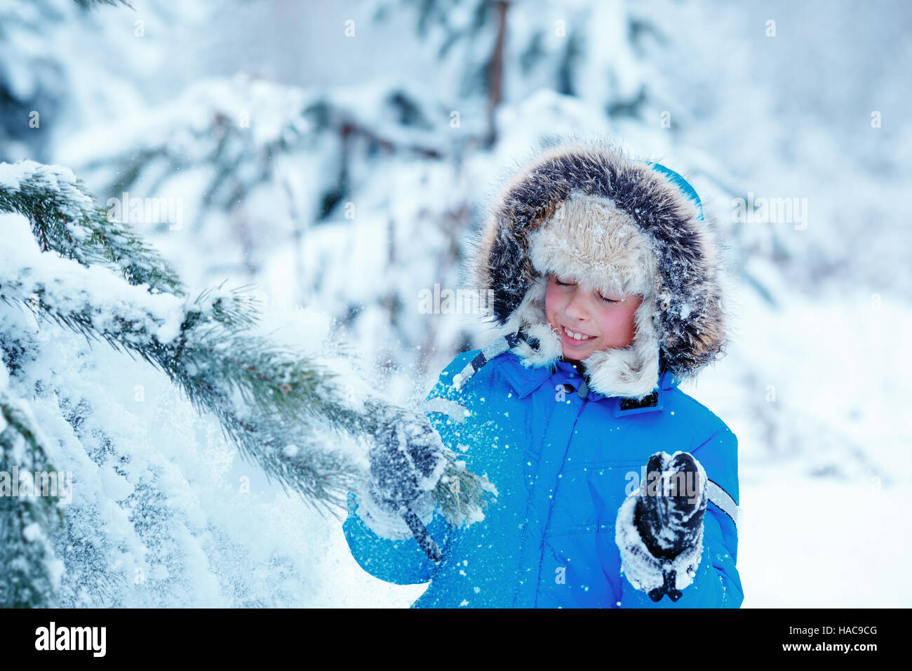Cute little boy wearing warm clothes playing on winter forest Stock Photo