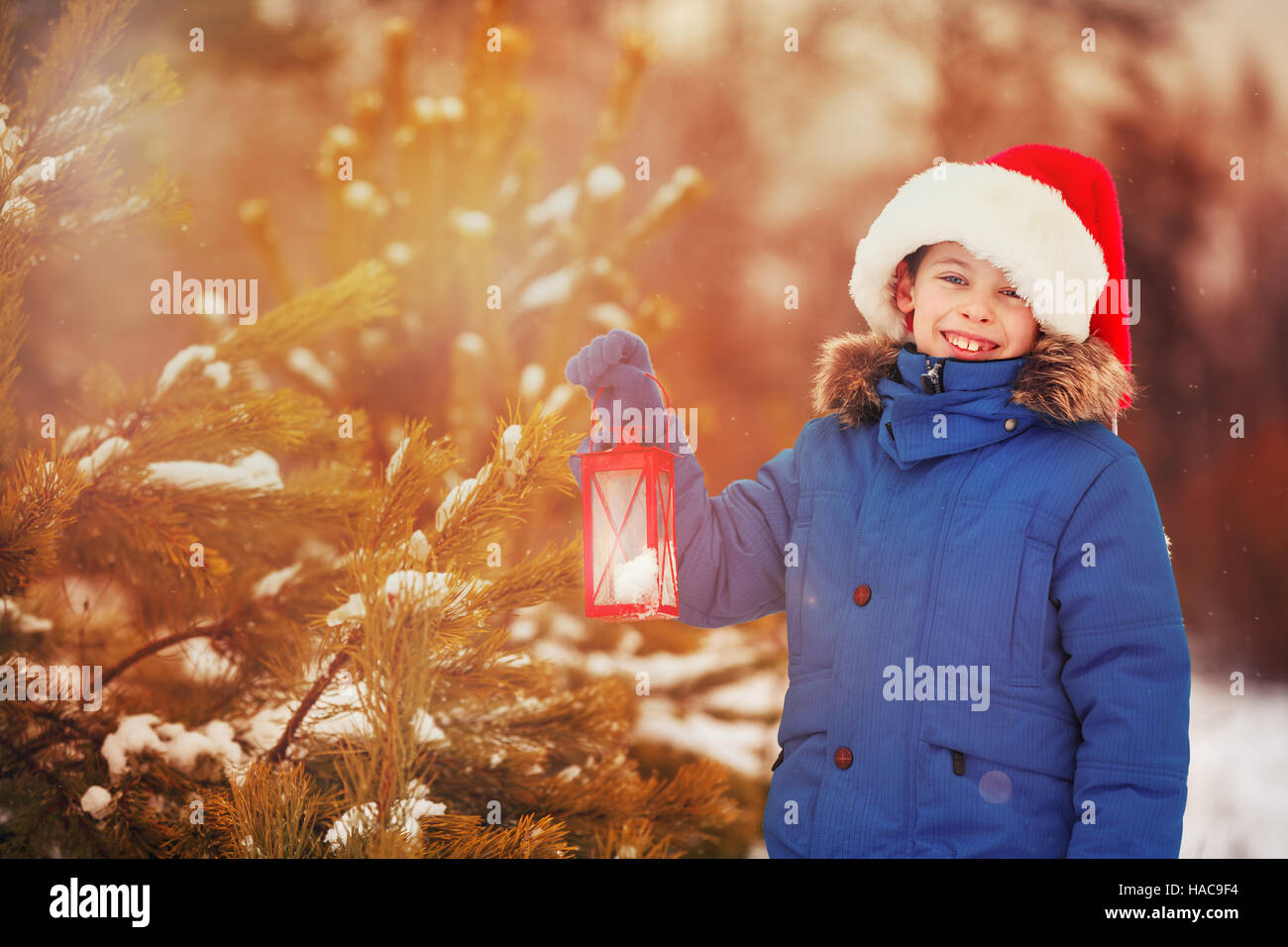Cute little boy holding Christmas lantern outdoors on beautiful winter snow day Stock Photo