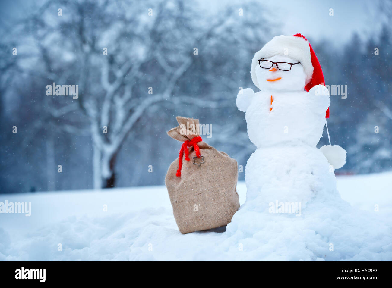 Snowman in Santa hat and sackcloth bag on winter day Stock Photo