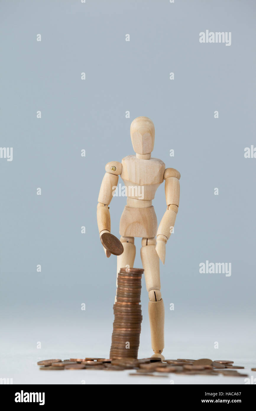 Wooden figurine standing and making stack of coins Stock Photo - Alamy