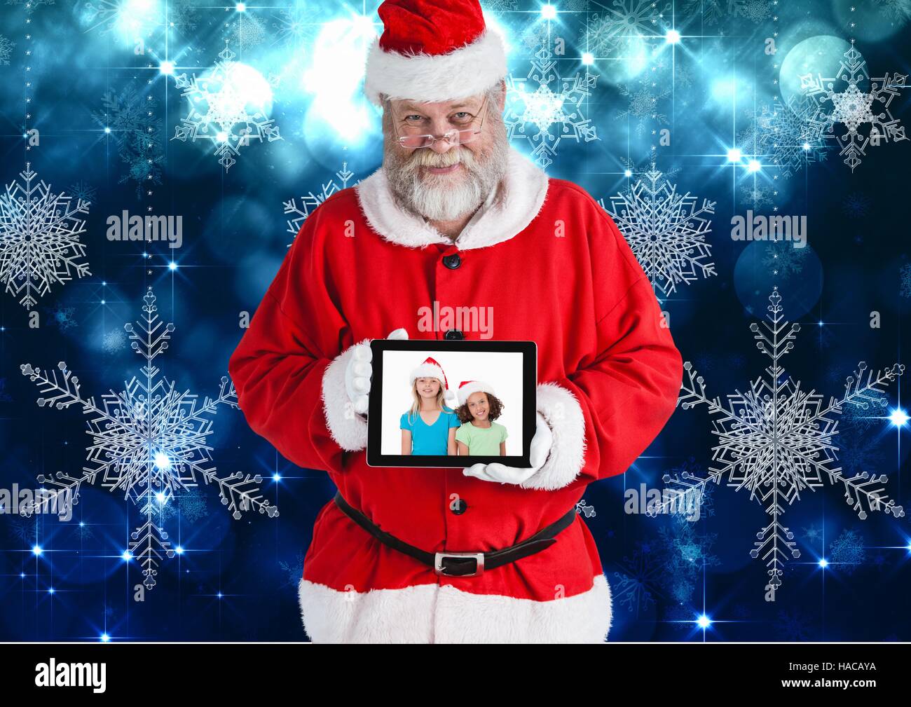 Santa claus holding a digital tablet with photo of christmas kids Stock Photo