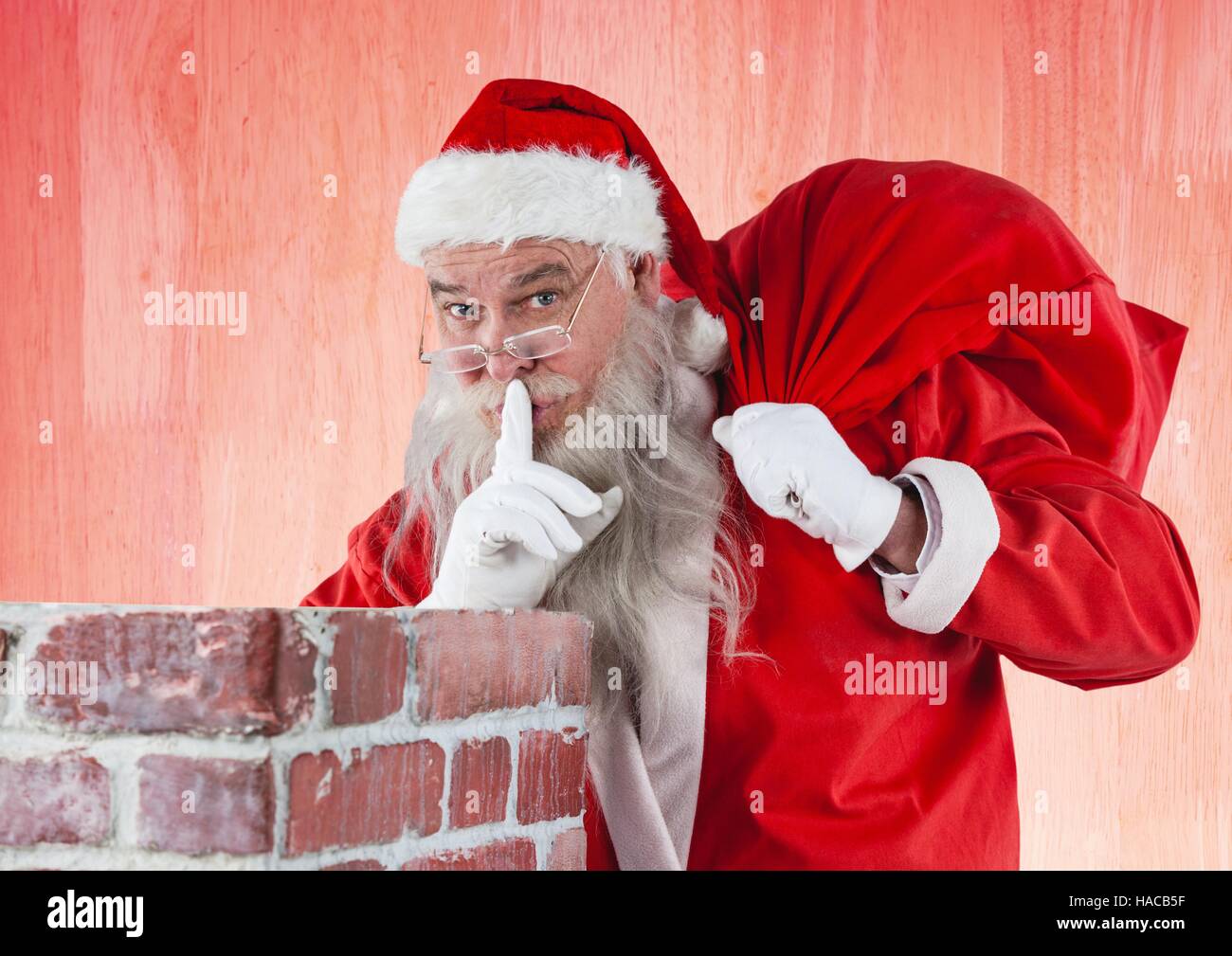 Santa claus with finger on lips carrying gift bag Stock Photo