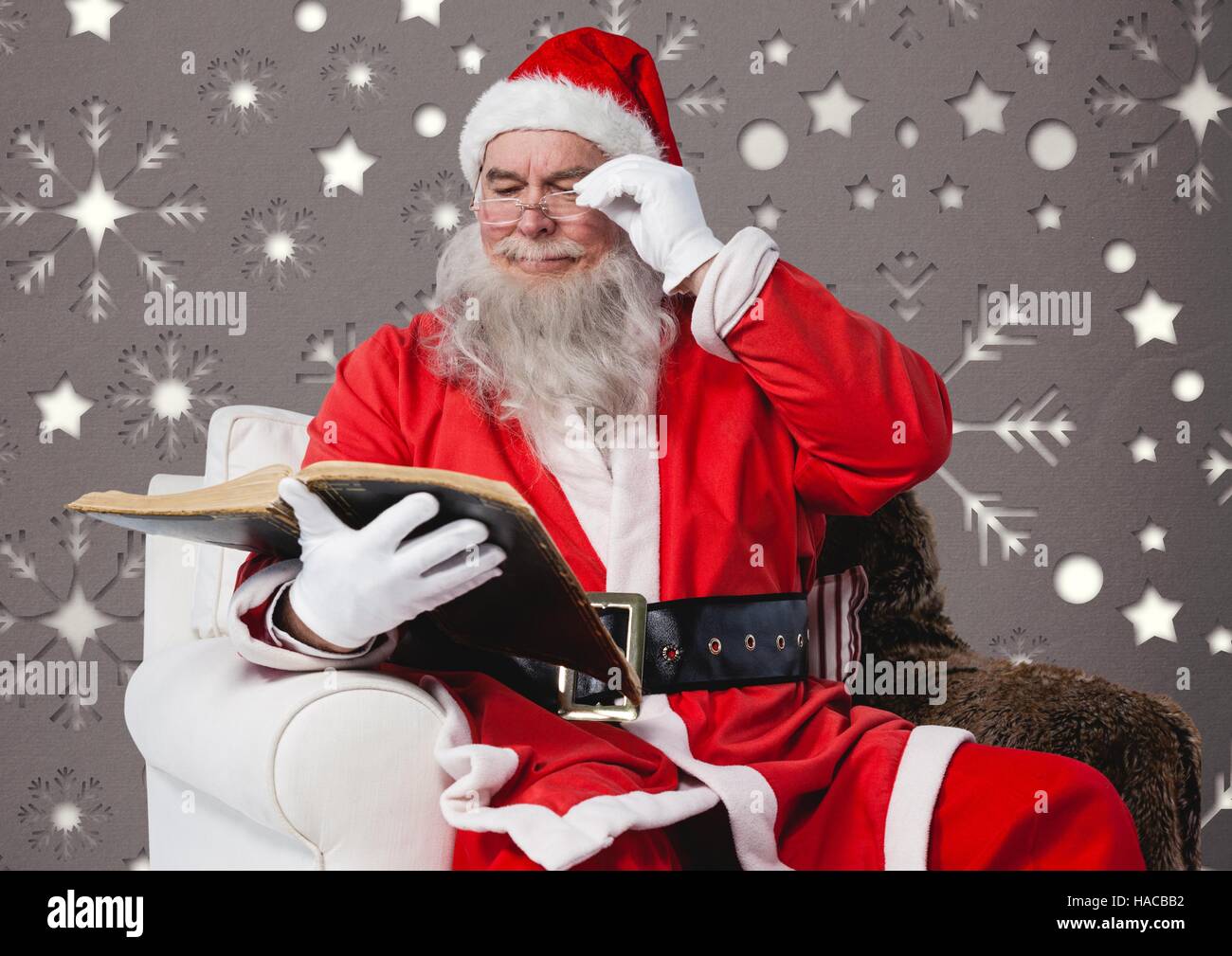 Santa claus reading a book while sitting on a chair Stock Photo