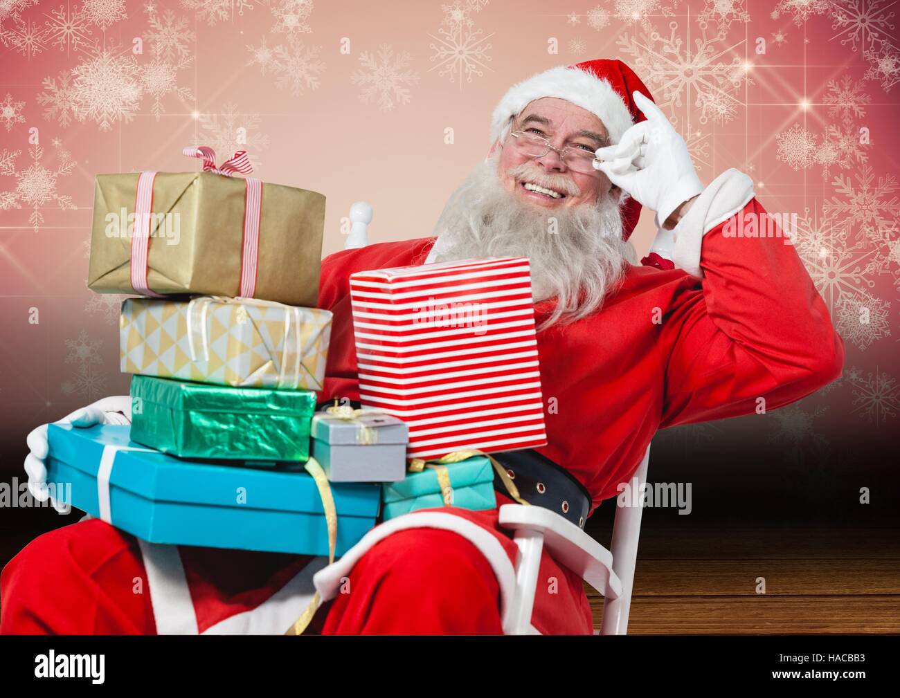 Happy santa sitting on chair with christmas gifts Stock Photo
