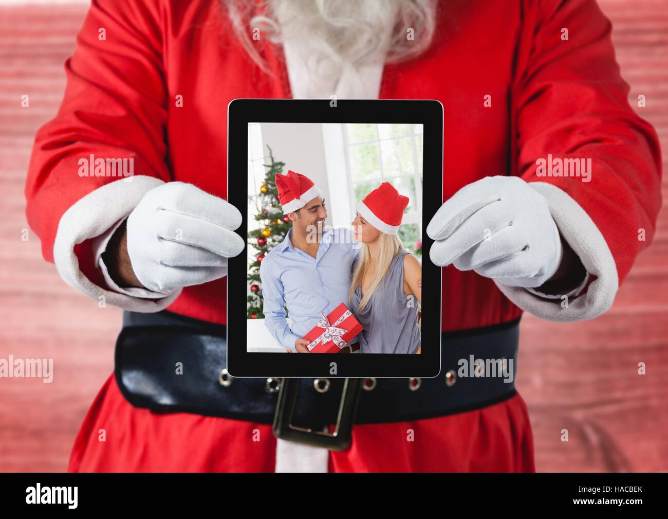 Santa claus holding a digital tablet with photo of christmas couple Stock Photo