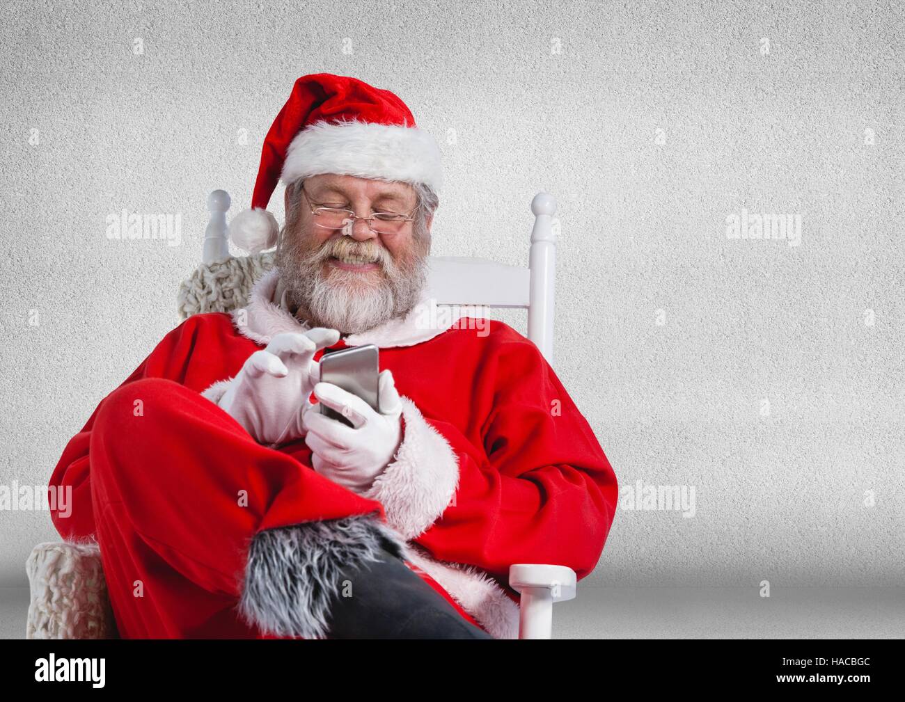 Happy santa sitting on chair and using mobile phone Stock Photo