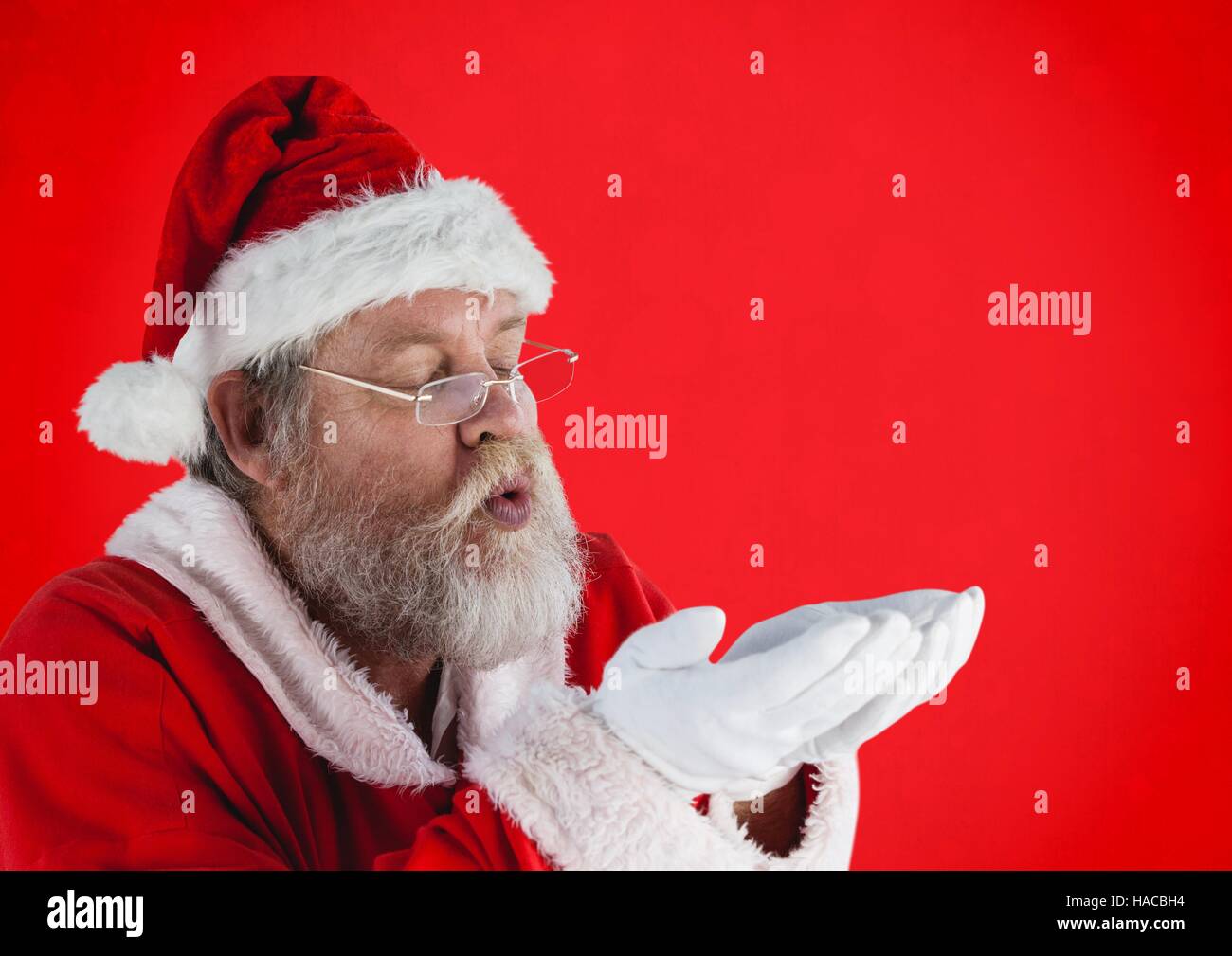 Santa claus pretending to blow imaginary snow Stock Photo