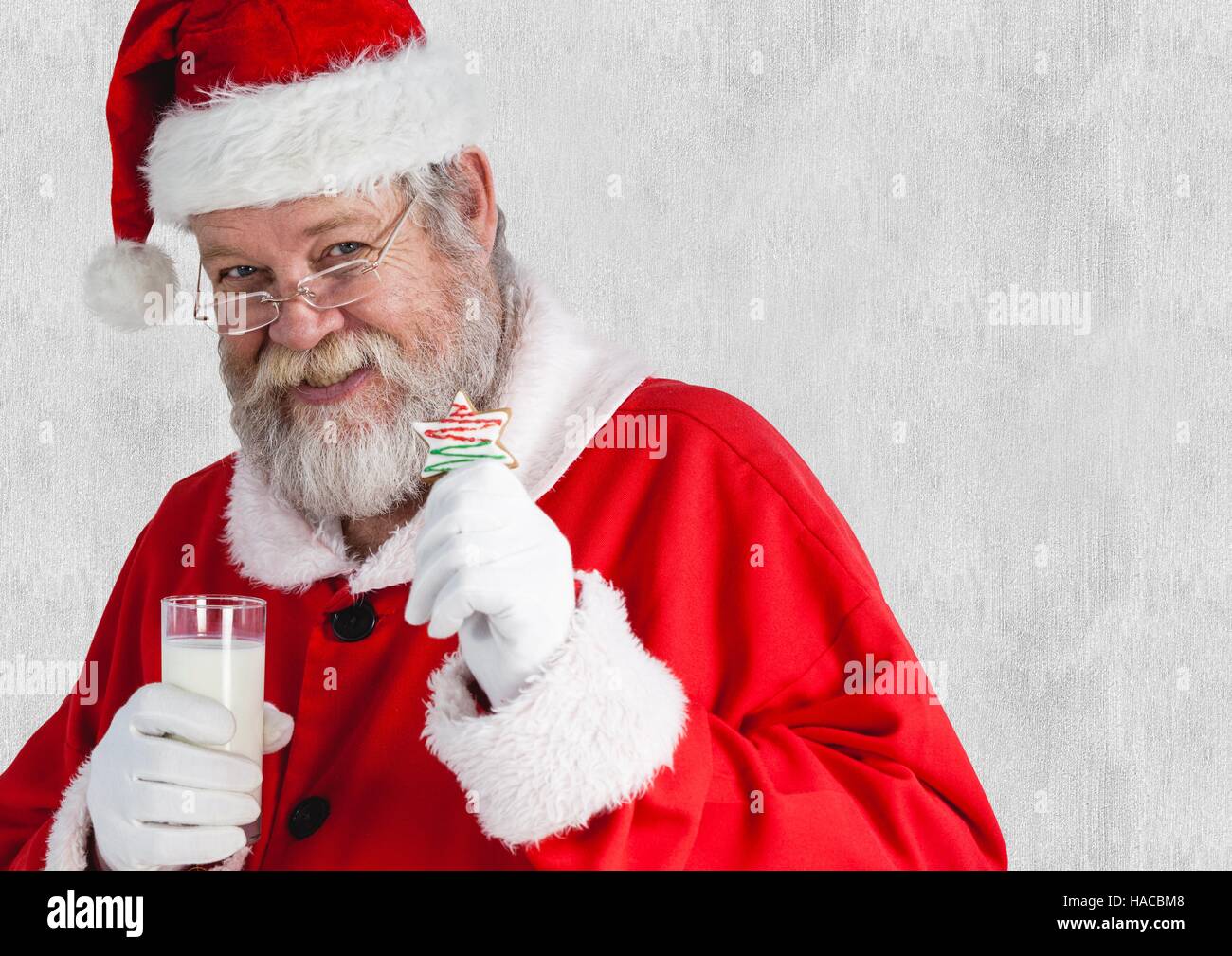 Santa claus holding glass of milk and cookies Stock Photo