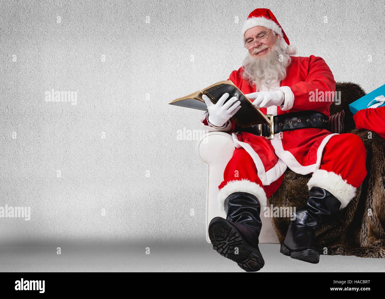 Santa sitting on sofa and reading book Stock Photo