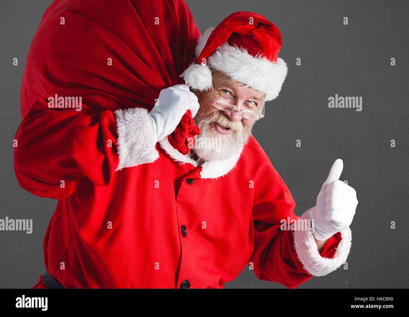 Santa with gift sack showing thumbs up Stock Photo - Alamy