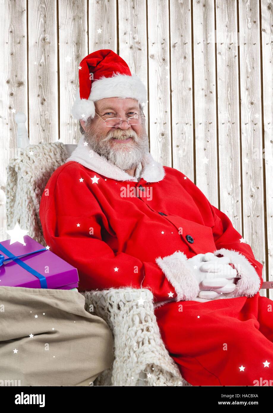 Happy santa sitting on chair with gifts Stock Photo