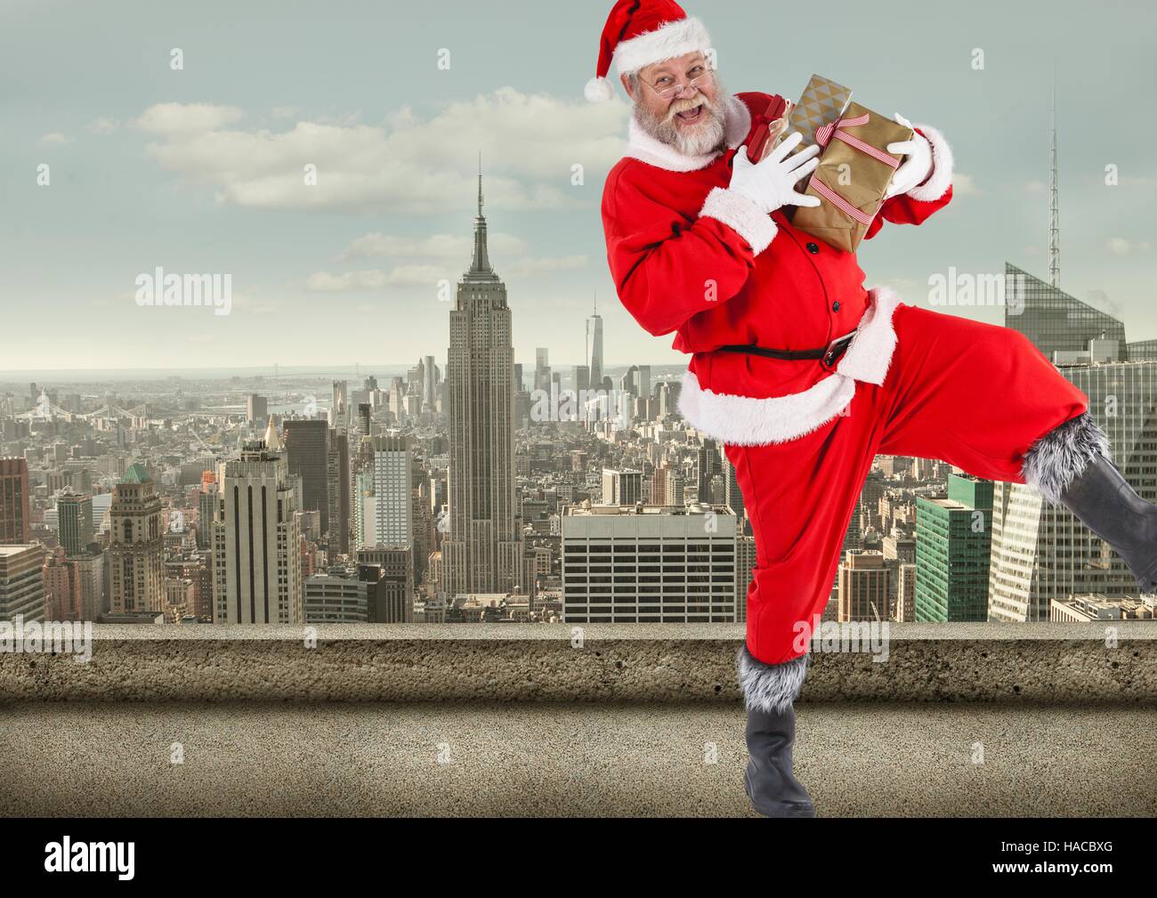 Santa claus  holding gift boxes standing on balcony of a building Stock Photo