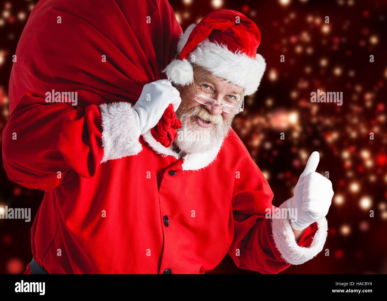 Santa claus carrying gift bag showing thumbs up sign Stock Photo - Alamy