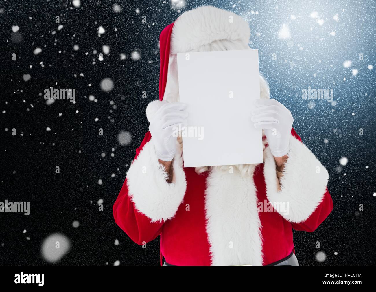 Santa holding blank card in front of his face Stock Photo