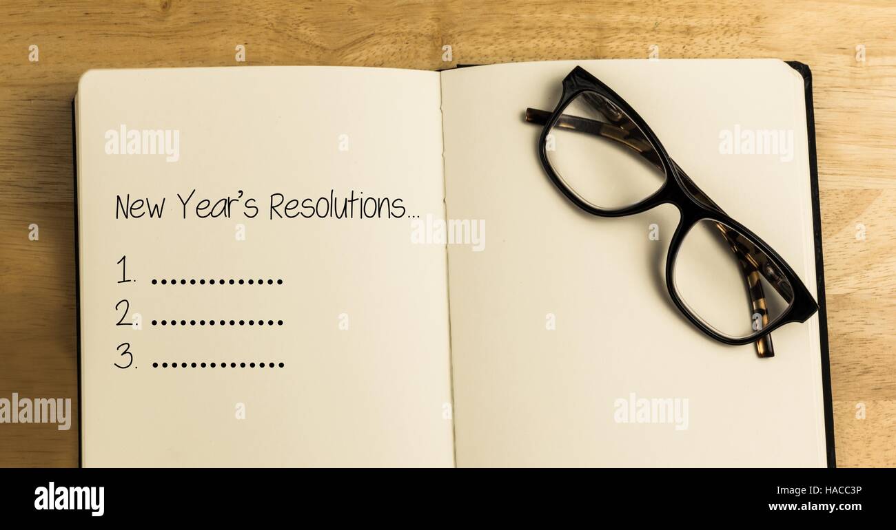New year resolution goals in book with spectacles against wooden background Stock Photo