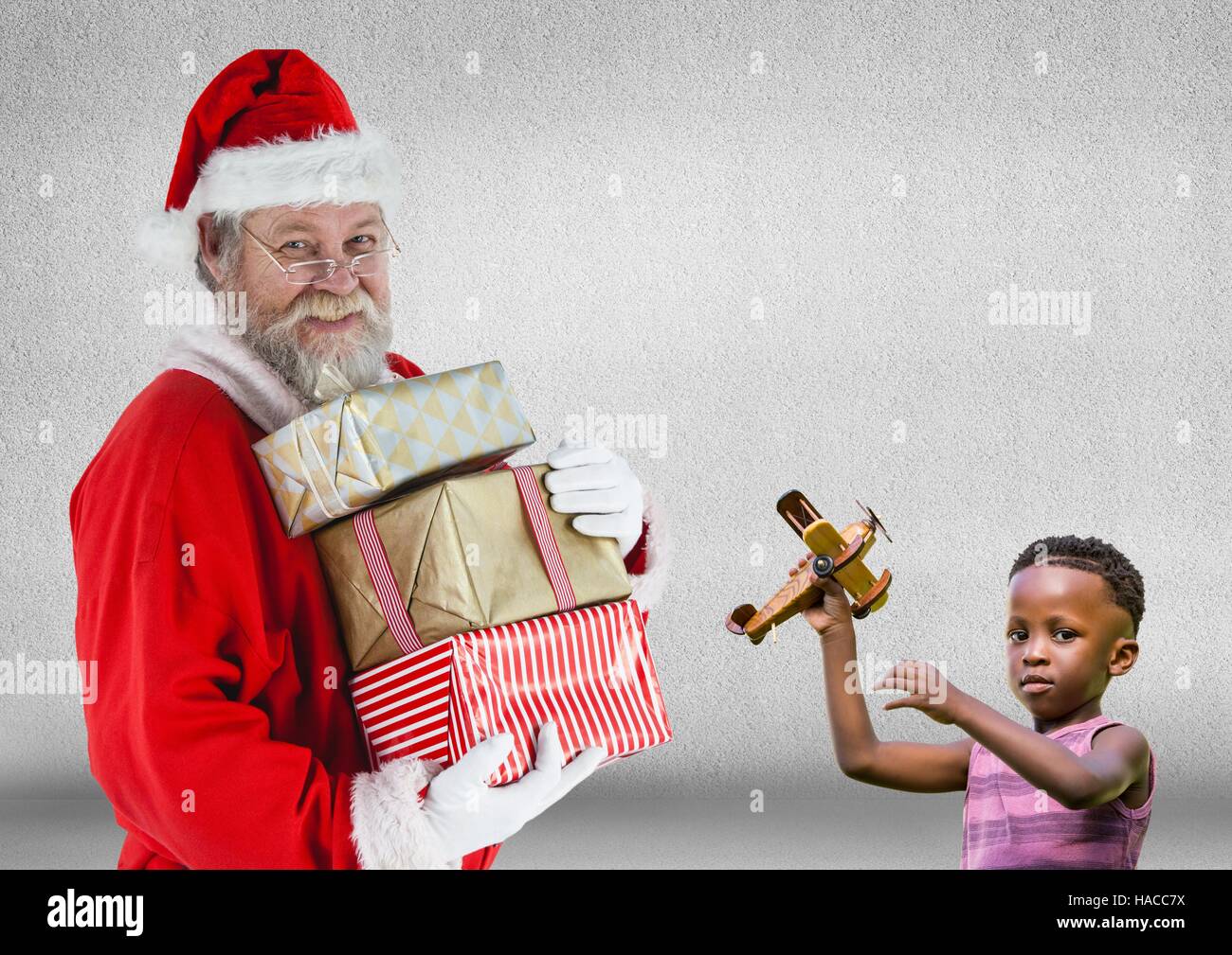 Santa claus holding stack of christmas gifts and boy with a toy Stock Photo