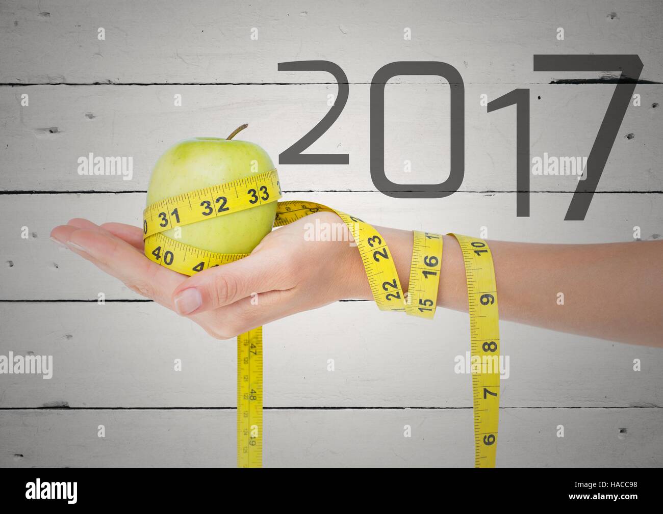 Hand holding green apple wrapped with measuring tape against 2017 Stock Photo