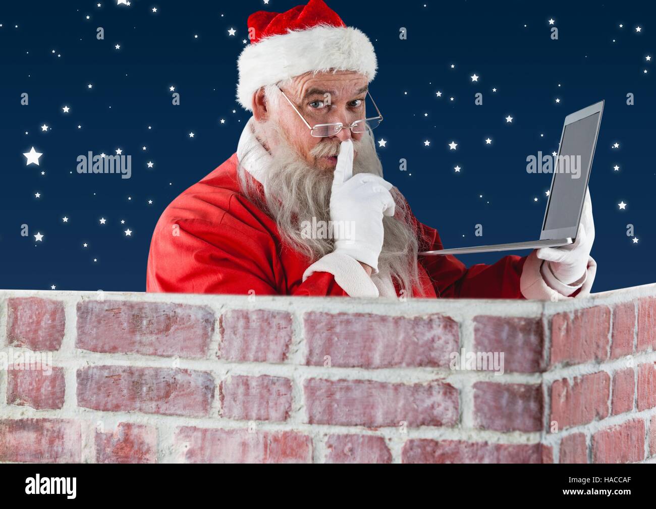 Santa with finger on lip using laptop Stock Photo