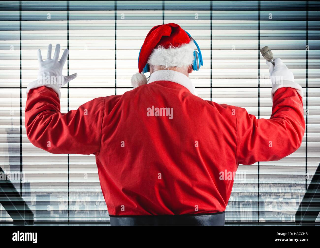 Santa listening to headphones against window Stock Photo