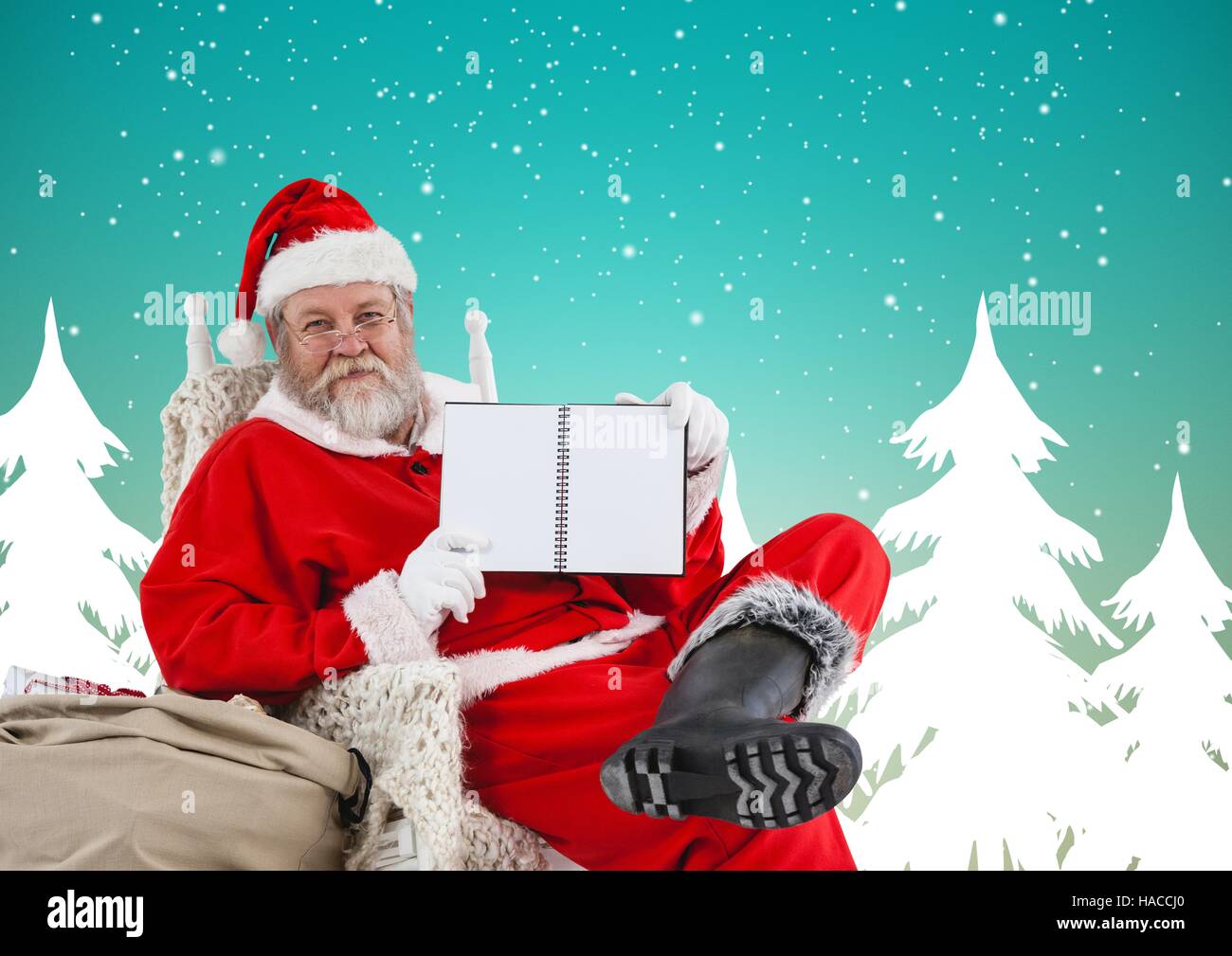 Santa claus sitting on chair and showing blank diary Stock Photo